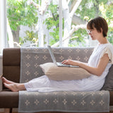 シュニールコットンブランケット シャーンスンド ハーフサイズ グレーを掛けたソファの上で座ってパソコン作業をする女性を正面から見たシーン
