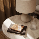 トラバーチン テーブル カシミア ラージの上に本やグラスを置いたイメージシーン